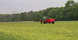 SL 124 off in the distance spreading manure in a field.