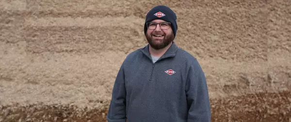 Man stands in front of silage bunker with KUHN hat and KUHN sweatshirt